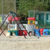 Un parco giochi colorato su una spiaggia con altalene e scivoli.