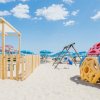 Spiaggia con giochi colorati e ombrelloni blu.