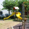 Scivolo giallo in un parco giochi con alberi.