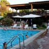 Piscina con ombrelloni bianchi e una terrazza coperta in legno. Persone vicino e dentro l'acqua.