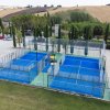 Due campi da padel blu, recintati, in un'area esterna.