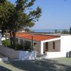 Edifici bianchi con tetto rosso, alberi, vista sul mare.