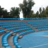 Anfiteatro all'aperto con file di sedili blu e alberi sullo sfondo.