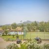 Campo da calcio recintato vicino a una piscina all'aperto. Sullo sfondo, colline e vegetazione.