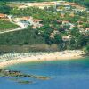 Una spiaggia con ombrelloni vicino a una scogliera e case sulla collina.