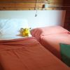 Due letti singoli con coperte arancioni e un peluche giallo tra i cuscini.