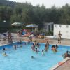 Una piscina all'aperto affollata, circondata da lettini e ombrelloni gialli e blu.