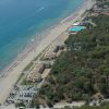 Spiaggia con strutture alberghiere e area alberata.