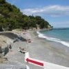 Spiaggia di ciottoli con lettini e mare calmo.