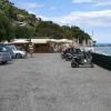 Un parcheggio con auto e scooter vicino al mare.
