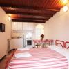 Monolocale con letto matrimoniale a righe rosse, cucina e tavolo. Decorazioni luminose.