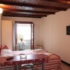 Camera con letto matrimoniale, televisore e porta verso un balcone.