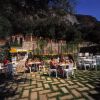 Persone sedute all'aperto a tavoli bianchi in un giardino.