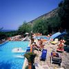 Piscina all'aperto con scivolo e lettini, vista mare.