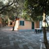 Vialetto tra case arancioni circondate da alberi.