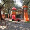 Scivoli e giochi per bambini in un parco giochi ombreggiato.