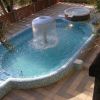 Piscina con fontana al centro, circondata da alberi.