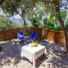 Sdraio e tavolino su terrazza vista mare circondata da alberi.