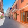 Una strada pedonale con hotel e ristoranti, persone che passeggiano.