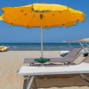 Spiaggia con lettini bianchi e ombrellone giallo.