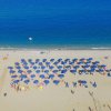 Spiaggia con ombrelloni blu vista dall'alto.