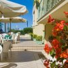 Terrazza esterna con tavoli, sedie e fiori.