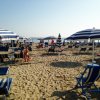 Spiaggia con sabbia, sedie a sdraio e ombrelloni.
