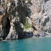 Formazione rocciosa ad arco sulla costa con mare blu al di sotto.
