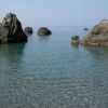 Scogliere immerse in acqua cristallina con alcune persone che nuotano.