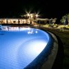 Piscina illuminata di notte con sedie a sdraio.