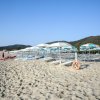 Spiaggia sabbiosa con lettini e ombrelloni.