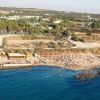 Spiaggia affollata con ombrelloni e mare azzurro.