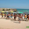 Persone giocano sulla spiaggia con ombrelloni colorati.