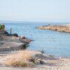Spiaggia rocciosa con persone che nuotano.