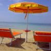 Due lettini arancioni e un ombrellone sulla spiaggia.