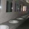 Un bagno pubblico con una lunga fila di lavandini e specchi.