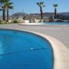 Piscina curva con palme e rocce decorative.
