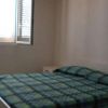 Una camera con letto matrimoniale a quadri blu e verdi, vicino a una finestra con persiane.