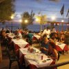 Cena all'aperto al tramonto, con tavoli apparecchiati e persone che conversano.
