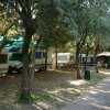 Area campeggio con camper all'ombra degli alberi.