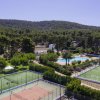 Complesso sportivo con campi da tennis, piscina e alberi circostanti.