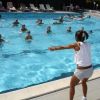 Istruttrice guida esercizi in una piscina con partecipanti in acqua.