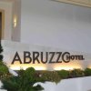 Ingresso di un hotel con una donna accanto al cartello Abruzzo Hotel.