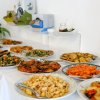 Tavolo buffet con piatti di verdure, patate e altri contorni.
