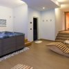 Una spa interna con vasca idromassaggio, lettini in legno e sauna.