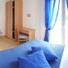 Camera da letto con letto matrimoniale blu, finestre con tende azzurre, scrivania e TV.
