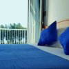 Camera con letto matrimoniale, cuscini e coperte blu, vista su balcone con alberi.