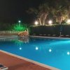 Piscina illuminata di notte con lettini e alberi sullo sfondo.