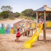 Bambini che giocano su uno scivolo in spiaggia.