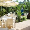 Tavoli con sedie bianche all'aperto, ombrelloni gialli e piante tropicali.